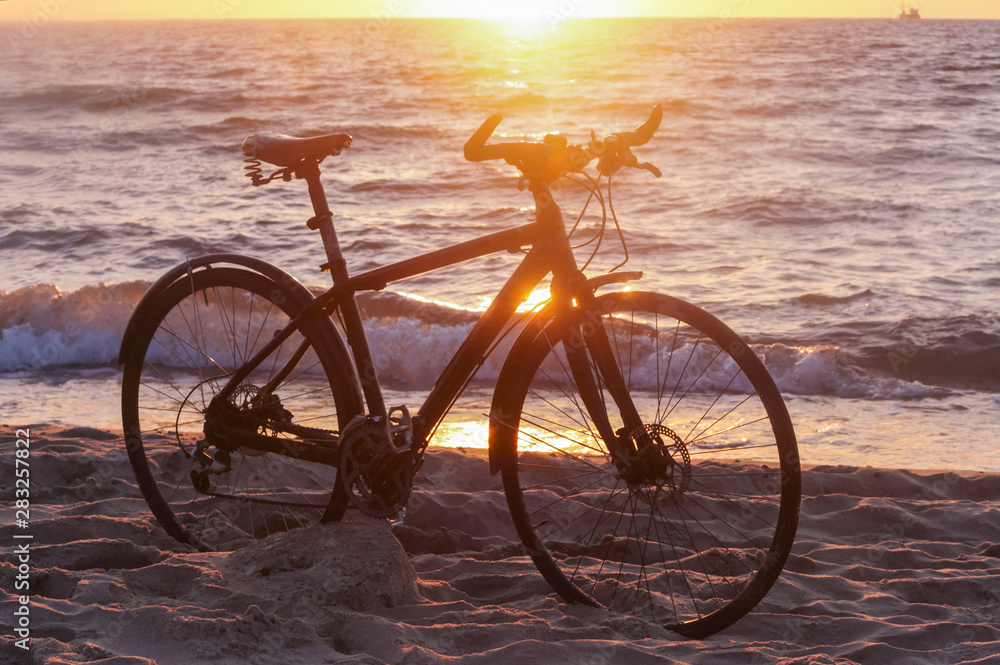 Fototapeta premium Bike and sunset by the sea. Black bike by the sea.