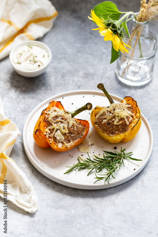 Stuffed paprika with meat, quinoa and cheese on a plate. Baked stuffed yellow orange peppers.