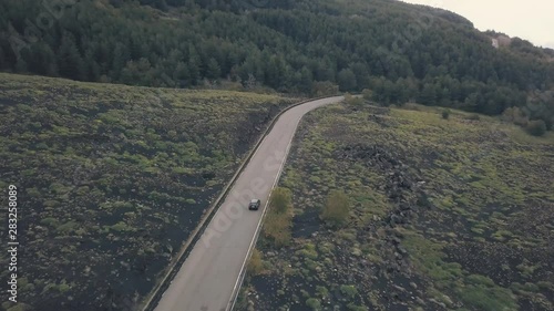 Aerial view of the slope of Mount Etna. Flying drone over the road on which the car is traveling. Italy, Sicily