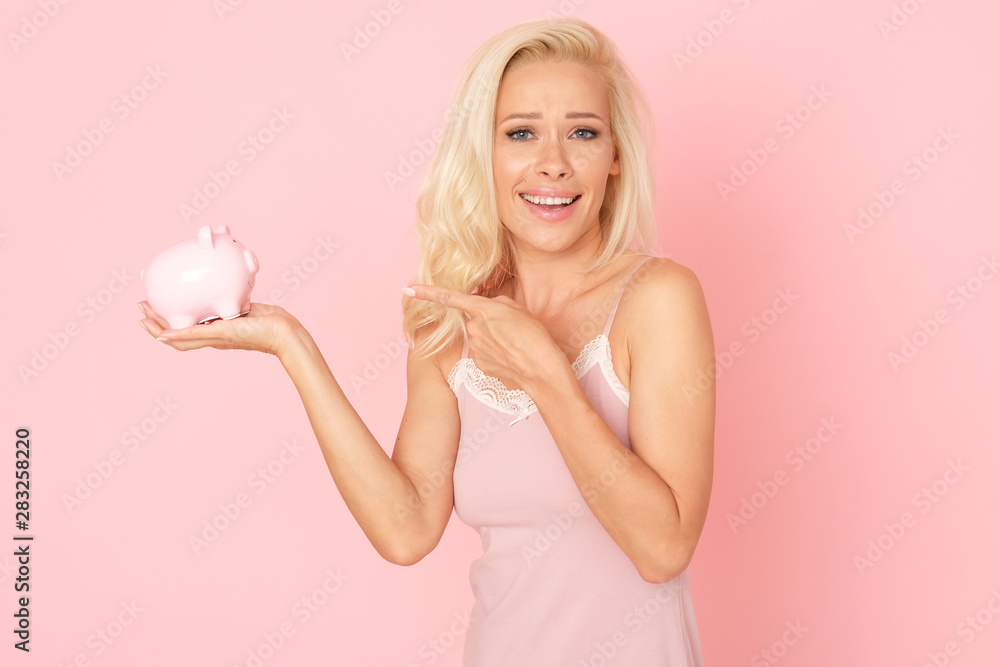 Beautiful blonde woman is saving money in her porcelain piggy bank. Beautiful blonde woman is saving money in her porcelain piggy bank.