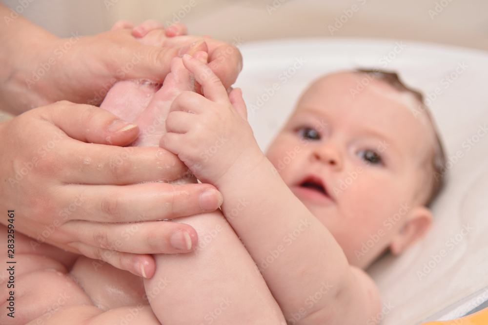 Pretty three months baby girl taking a bath by her mother at home, european child. Pretty three months baby girl taking a bath by her mother at home, european child.