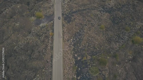 Aerial view of the slope of Mount Etna. Flying drone over the road on which the car is traveling. Italy, Sicily