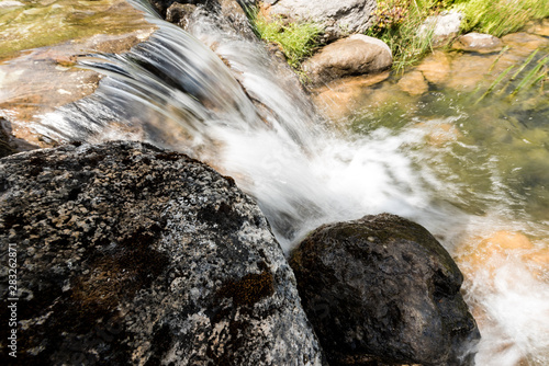 steam with water flowing on rocks near grass in park