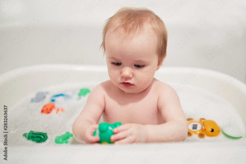 Cute little girl playing with rubber toys in small bathtub Cute little girl playing with rubber toys in small bathtub
