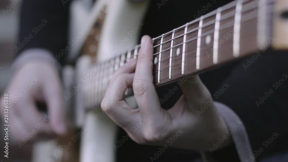 Close up of guitarist fingers playing an electric guitar, with a shallow depth of field. Close up of guitarist fingers playing an electric guitar, with a shallow depth of field.