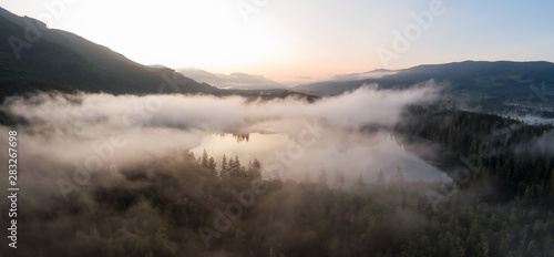 Aerial Panoramic View of Fairy Lake covered in clouds during a vibrant summer sunrise. Taken near Port Renfrew, Vancouver Island, British Columbia, Canada. © edb3_16