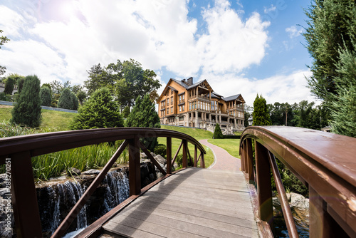 selective focus of wooden bridge near green park and luxury house