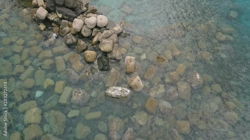 Aerial view of the sea coast. Waves splashing near a stone beach. Azure clear water. Aerial view of the sea coast. Waves splashing near a stone beach. Azure clear water.