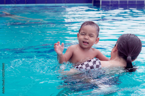 asian mother and baby in swimming pool. little baby having fun in a swimming pool at thailand