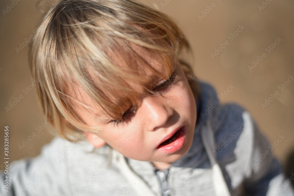 Blond kid walking on the beach in light clothes. Cold summer day. A lonely boy on the river Bank. Emotions. Suffering, unhappiness, sadness, sadness, tears, pain, loss.