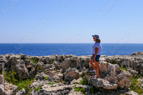 Syracuse, Sicily, Italy A tourist at the Capo Murro di Porco Lighthouse at the end of the Maddalena Peninsula on the south eastern tip of Sicily on the Ionian Sea.