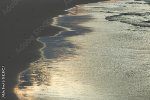 Wet sand on the beach lit by the evening sun closeup. Natural abstract background