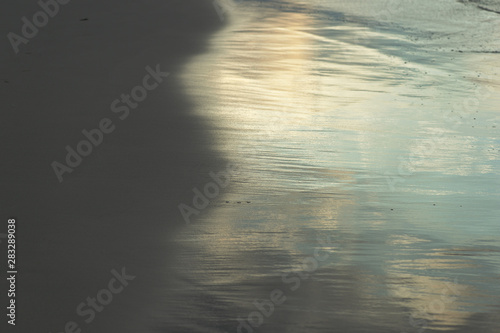 Wet sand on the beach lit by the evening sun closeup. Natural abstract background