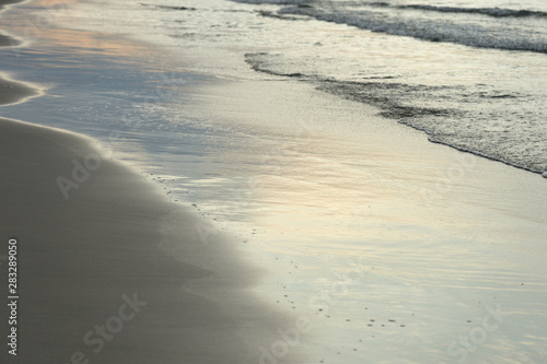 Wet sand on the beach lit by the evening sun closeup. Natural abstract background