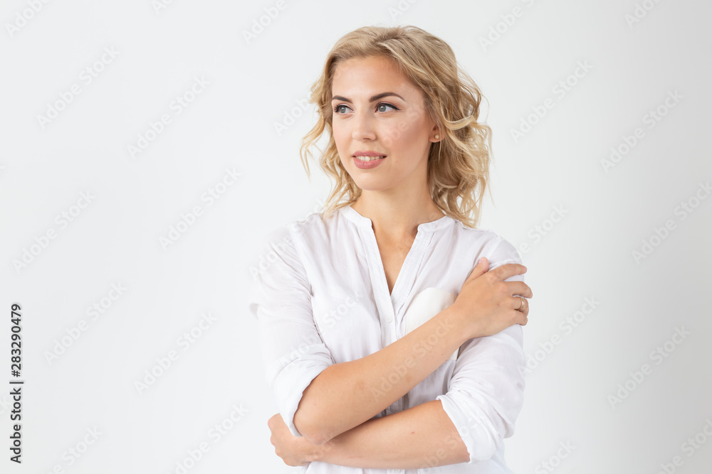 Cheerful young blond woman with long curly hair posing on a white background with copy space. The concept of a beautiful and well-groomed woman Cheerful young blond woman with long curly hair posing on a white background with copy space. The concept of a beautiful and well-groomed woman