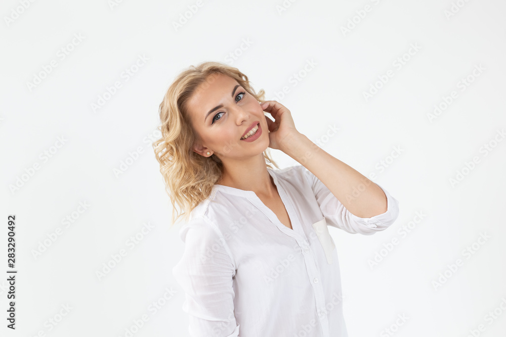 Cheerful young blond woman with long curly hair posing on a white background. The concept of a beautiful and well-groomed woman Cheerful young blond woman with long curly hair posing on a white background. The concept of a beautiful and well-groomed woman