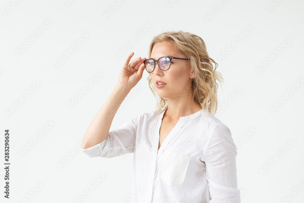 Portrait of concentrated beautiful woman with bad vision touching glasses isolated on white background Portrait of concentrated beautiful woman with bad vision touching glasses isolated on white background