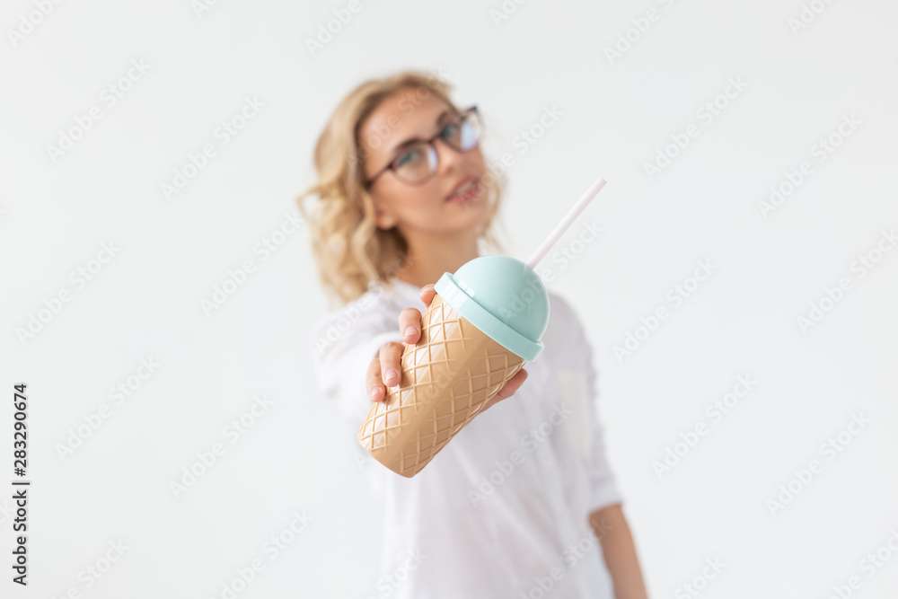 Cute charming young woman is holding a cocktail from a straw posing against a white background. Cute charming young woman is holding a cocktail from a straw posing against a white background.