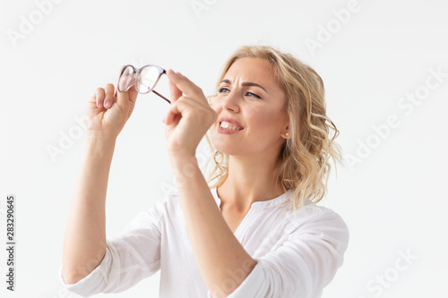 Vision, optics and beauty - Young blond woman putting on a pair of glasses on white background