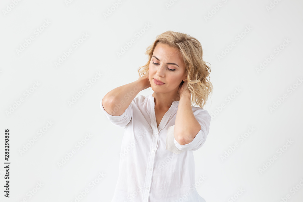 Cheerful young blond woman with long curly hair posing on a white background with copy space. The concept of a beautiful and well-groomed woman Cheerful young blond woman with long curly hair posing on a white background with copy space. The concept of a beautiful and well-groomed woman