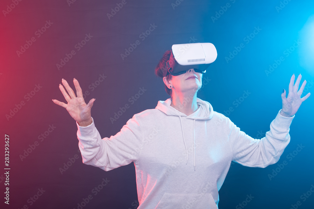 Smile happy woman getting experience using VR headset glasses of virtual reality on red-blue background Smile happy woman getting experience using VR headset glasses of virtual reality on red-blue background