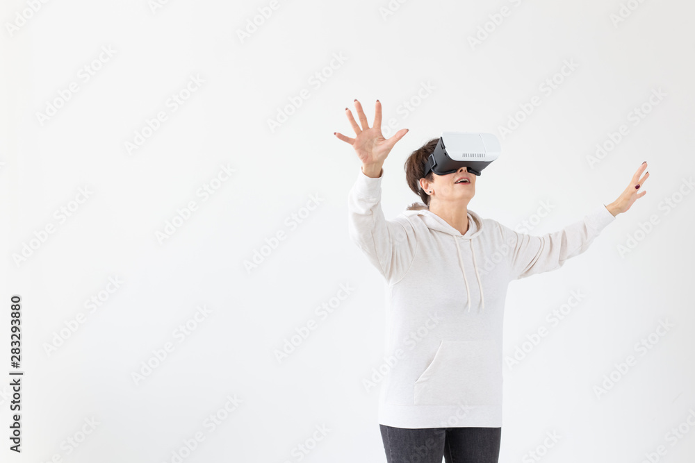 Positive pretty middle-aged woman in a white sweater watching a movie with glasses of virtual reality. The concept of futurism and new technologies. Positive pretty middle-aged woman in a white sweater watching a movie with glasses of virtual reality. The concept of futurism and new technologies.