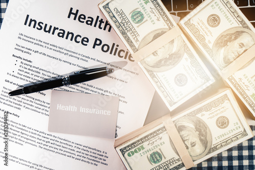 background of health insurance gold card member with pen on health insurance policy document and US bank note on table