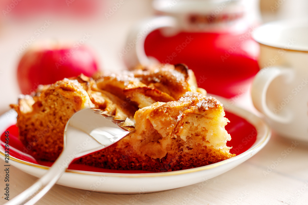 A piece of homemade apple pie on the plate with fork, fresh apple and cup of coffee close up A piece of homemade apple pie on the plate with fork, fresh apple and cup of coffee close up
