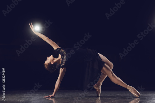 Woman ballet dancer on black background.