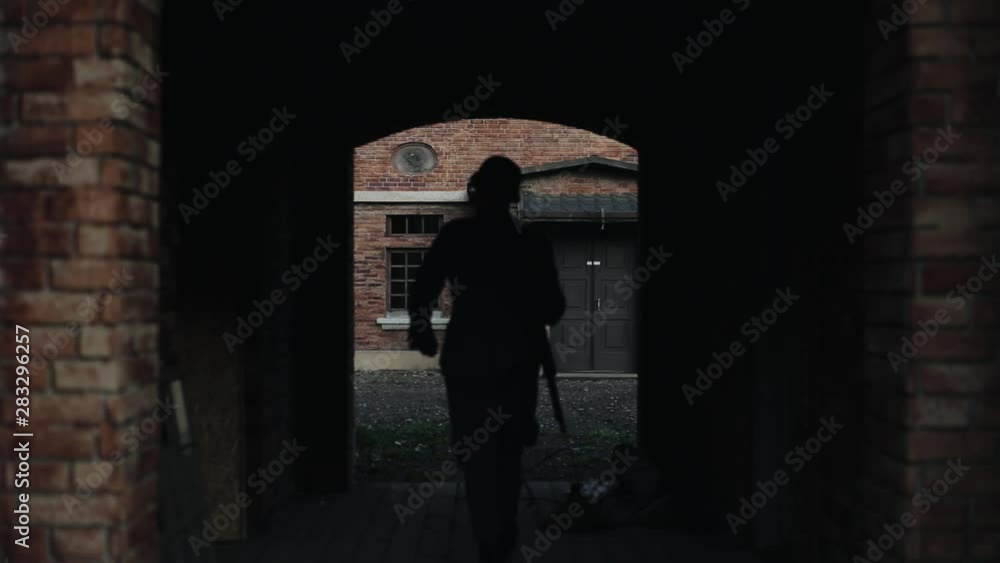 A German soldier walking slowly into a dark tunnel of an ancient red brick building. WWII reenactment A German soldier walking slowly into a dark tunnel of an ancient red brick building. WWII reenactment