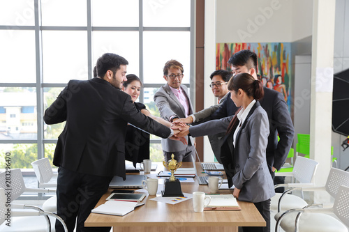 medium shot multiethnic business people stacking hands together meaning of teamwork concept