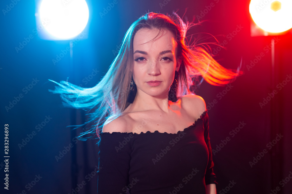 Naklejka premium Nightclub, nightlife and people concept - Young woman posing in the dark
