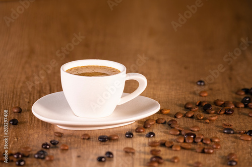 Beautiful white espresso cup surrounded by roasted coffee beans