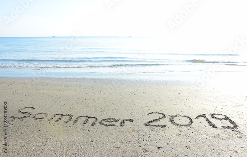Text Sommer 2019 in den Sand geschrieben am Meer bei Sonnenaufgang