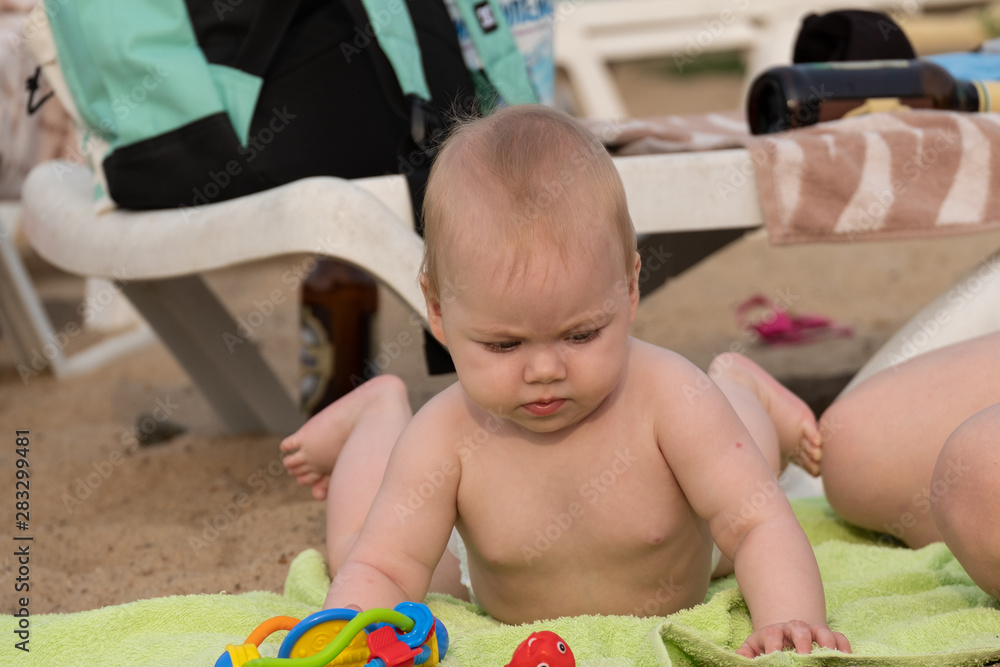 A little girl lying on the sand and playing with toys. A little girl lying on the sand and playing with toys.