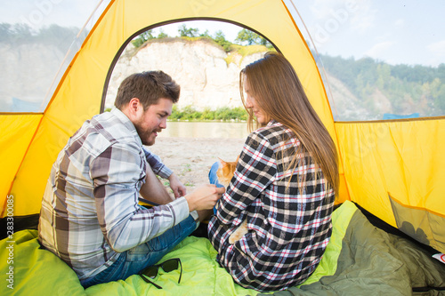 people, summer tourism and nature concept - young couple resting in camping tent, view from inside © satura_