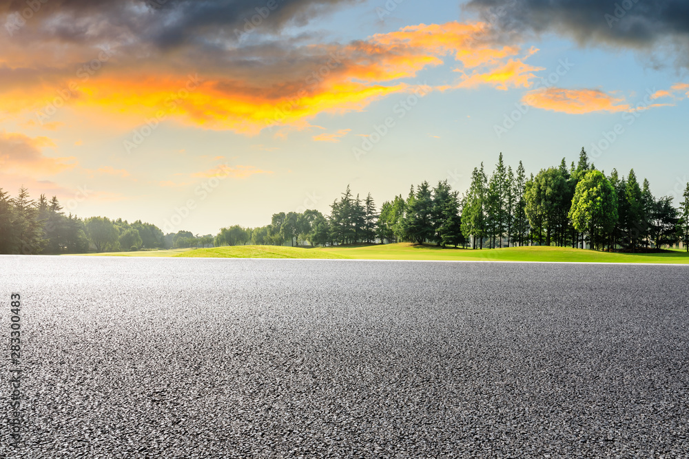 Country asphalt road and green woods nature landscape at sunset