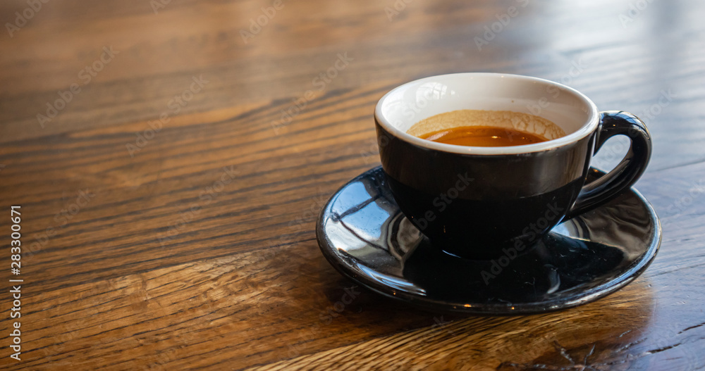 Espresso cup, black color with saucer on wooden table Espresso cup, black color with saucer on wooden table