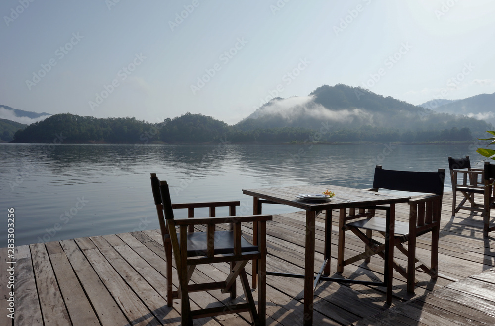 Dining table by the terrace on the middle of the water Behind the mountains Fog in the morning Dining table by the terrace on the middle of the water Behind the mountains Fog in the morning