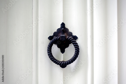 White wooden door with metal knocker in the form of a ring
