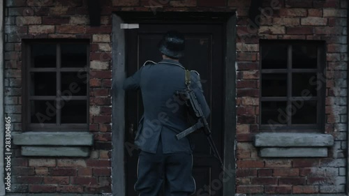 Wallpaper Mural A rear close-up of a German soldier knocking at the door and looking in the window of a red brick house. WWII reenactment Torontodigital.ca