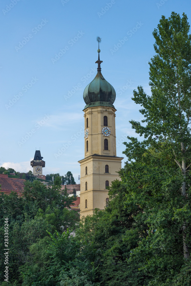 Mur river, the Franciscan Church tower and the famous clock tower (Grazer Uhrturm) in the background, in the centre of the city of Graz, Styria region, Austria