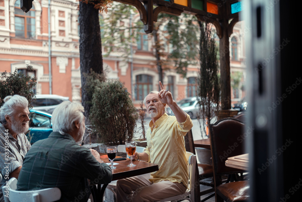 Man calling for waiter while sitting outside pub Man calling for waiter while sitting outside pub