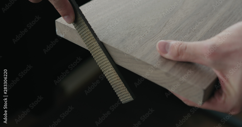Fototapeta premium woodworker hand sanding walnut board with file