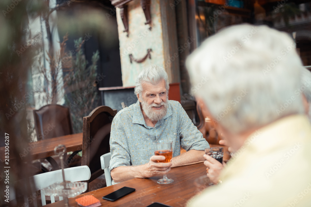 Bearded grey-haired man drinking alcohol with friends Bearded grey-haired man drinking alcohol with friends