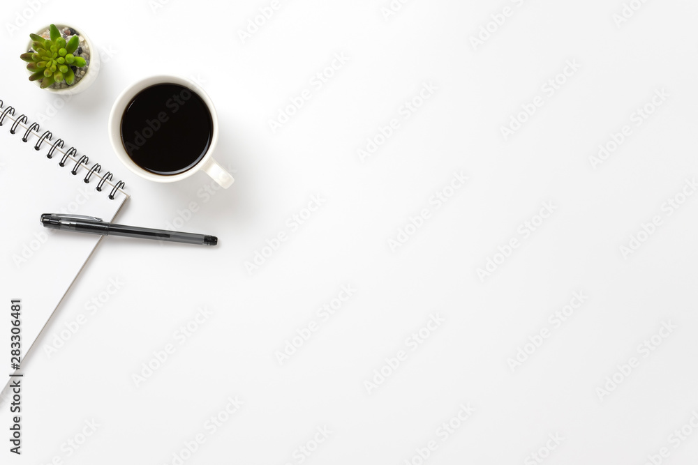 Flat lay, top view office table white desk. Workspace with notepad, pen, green leaf, and coffee cup on white background. Flat lay, top view office table white desk. Workspace with notepad, pen, green leaf, and coffee cup on white background.