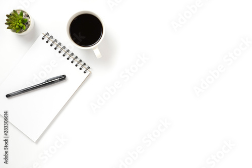 Flat lay, top view office table white desk. Workspace with notepad, pen, green leaf, and coffee cup on white background.