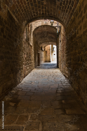 Architectural details of medieval stone and brick houses in a narrow passages at Volterra, Tuscany, Italy