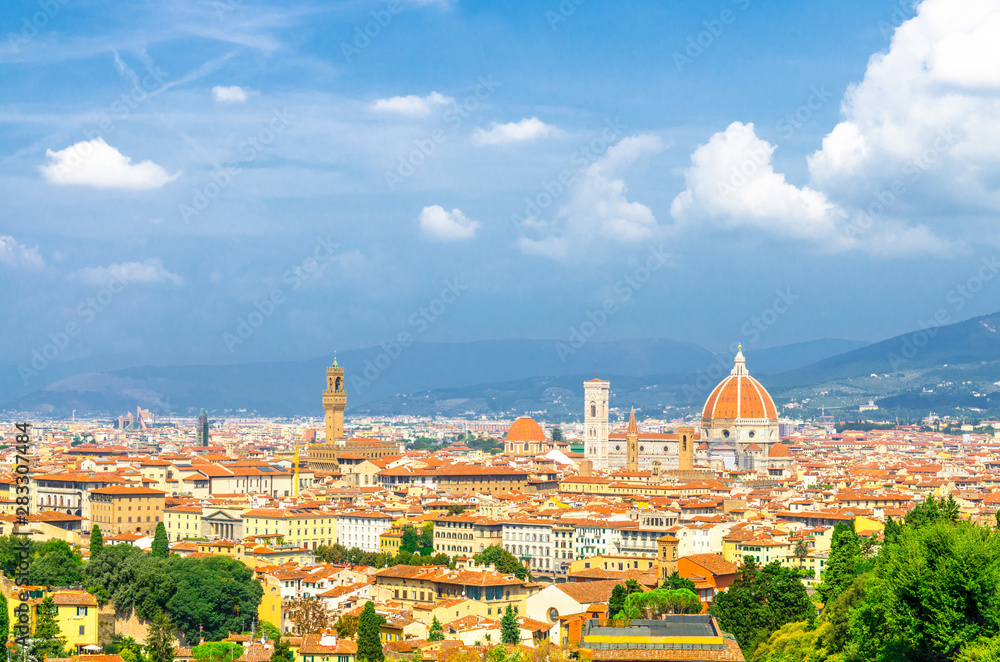 Obraz premium Top aerial panoramic view of Florence city with Duomo Cattedrale di Santa Maria del Fiore cathedral, buildings houses with orange red tiled roofs and hills range, blue sky white clouds, Tuscany, Italy