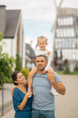 Father with daughter on neck walking with wife and his girl